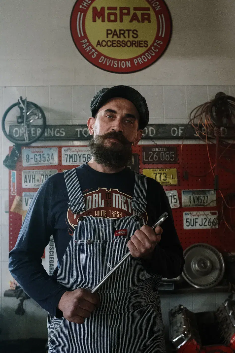 A mechanic in striped overalls holding a socket wrench in his workshop